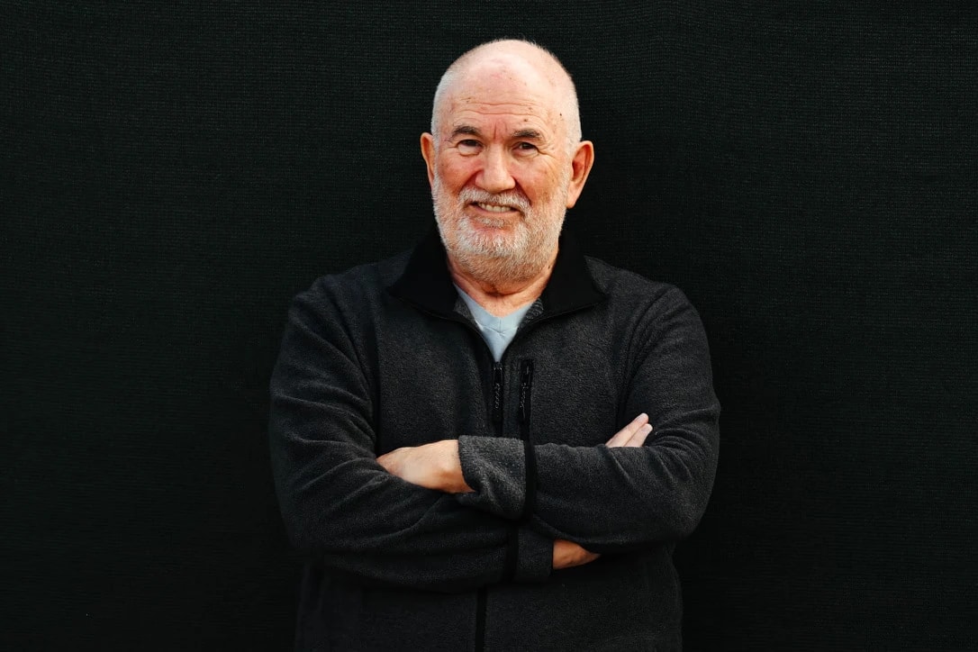 Tony Klinger, arms folded, against a black backdrop